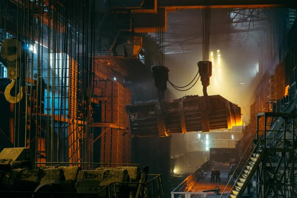 Interior de una acería: una cuchara de colada suspendida de una grúa sobre la nave de producción.